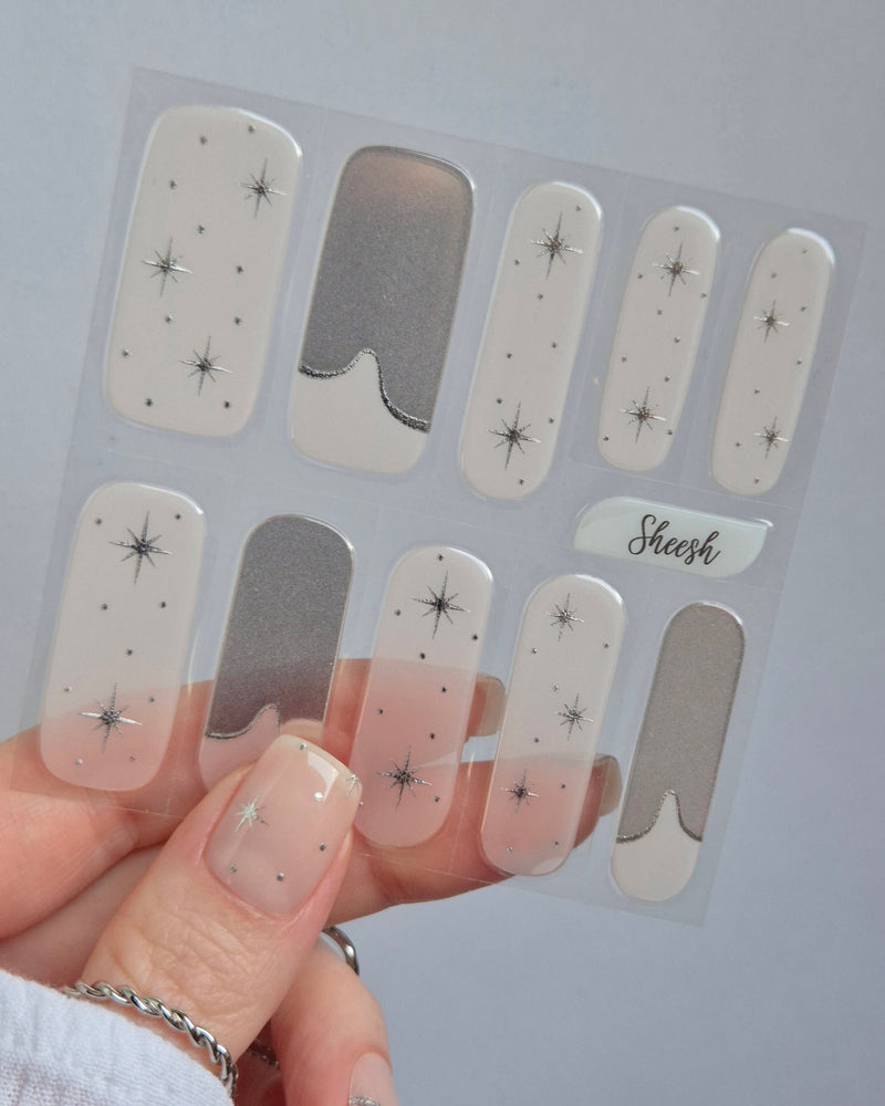 Sheesh Nails – Cosmic Crush – transparente Nagelfolien mit silbernem Glitzer und funkelnden Sternmotiven, elegantes Design für festliche Maniküren. Perfekte Passform und glänzendes Finish für einen modernen, glamourösen Nailart-Look.