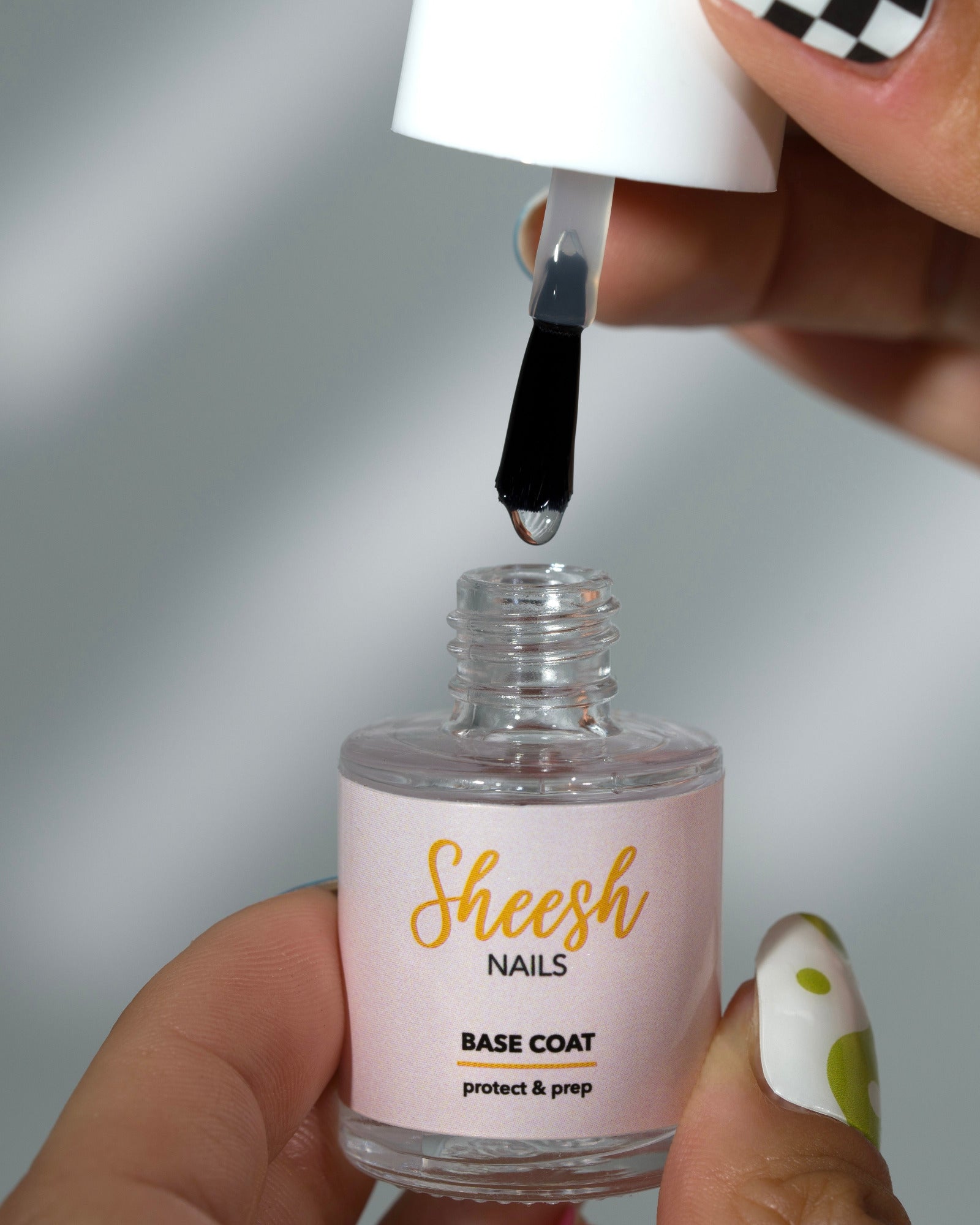 Produktfoto der Sheesh Nails „Base Coat“-Flasche mit weißem Deckel und beiger Etikettierung. Der Base Coat „Protect & Prep“ dient als schützende Grundierung für UV-Nagelfolien und sorgt für optimale Haftung sowie ein glattes, professionelles Ergebnis bei der Maniküre.