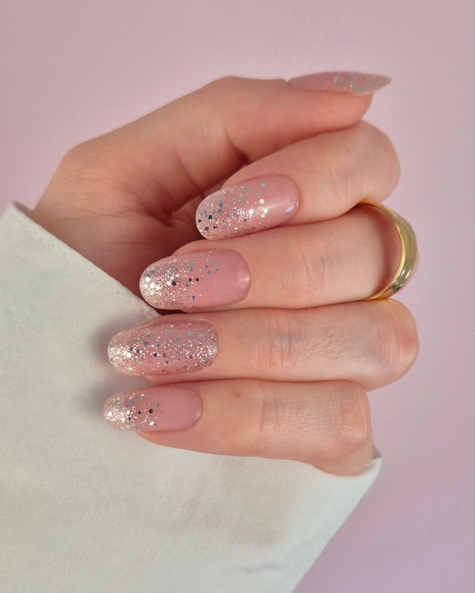 Nahaufnahme einer Hand mit der Sheesh Nails UV-Nagelfolie „Champagne Fizz“. Die Nägel zeigen ein zartes Nude-Rosa, das sanft in funkelnden Silberglitter übergeht. Der Look wirkt edel, festlich und feminin – perfekt für elegante Anlässe, festliche Looks oder einen stilvollen Alltagsglanz.