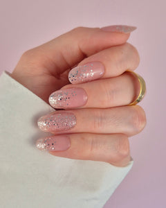 Nahaufnahme einer Hand mit der Sheesh Nails UV-Nagelfolie „Champagne Fizz“. Die Nägel zeigen ein zartes Nude-Rosa, das sanft in funkelnden Silberglitter übergeht. Der Look wirkt edel, festlich und feminin – perfekt für elegante Anlässe, festliche Looks oder einen stilvollen Alltagsglanz.