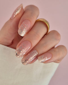 Nahaufnahme einer Hand mit der Sheesh Nails UV-Nagelfolie „Champagne Fizz“. Die Nägel zeigen ein zartes Nude-Rosa, das sanft in funkelnden Silberglitter übergeht. Der Look wirkt edel, festlich und feminin – perfekt für elegante Anlässe, festliche Looks oder einen stilvollen Alltagsglanz.