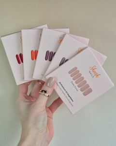 Sheesh UV-Nagelfolien 5er Set – Hand hält fünf verschiedene Sheesh Nagelfolien-Verpackungen in Salonqualität für individuelle Maniküre.