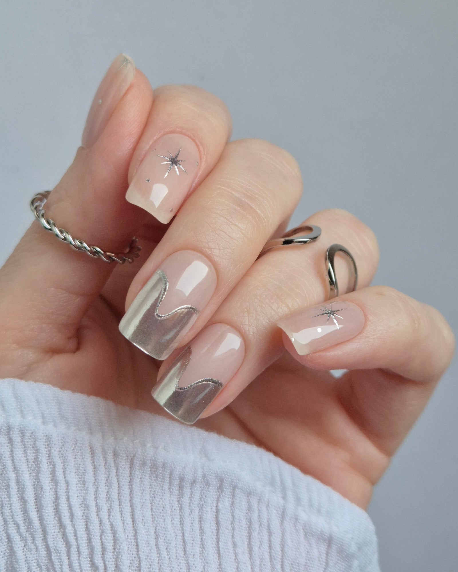 Sheesh Nails – Cosmic Crush – elegante Nagelfolien in transparentem Nude mit silbernem Glitzer und funkelnden Sternmotiven, stilvolles Design für moderne, glamouröse Maniküren. Perfekte Passform und glänzendes Finish für festliche Looks.