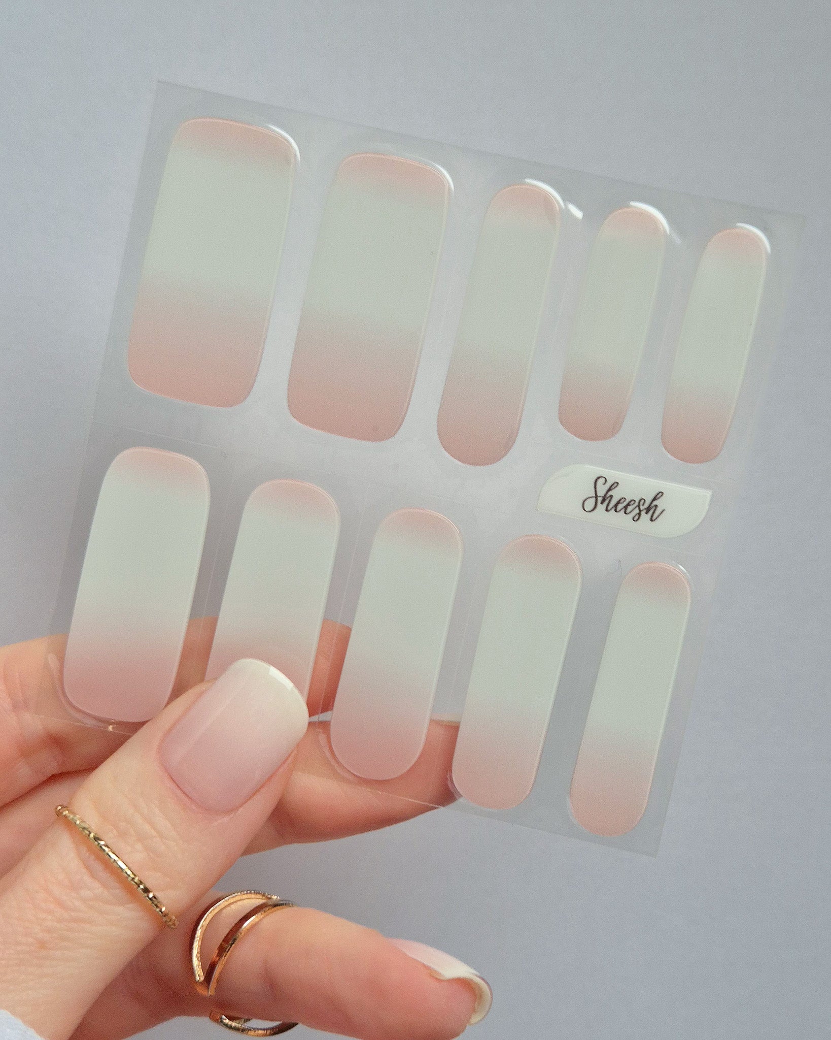 Babyboomer UV-Nagelfolie mit zartem Ombré-Finish in Rosa-Weiß auf Hand vor hellem Hintergrund