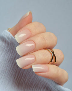 Babyboomer UV-Nagelfolie mit zartem Ombré-Finish in Rosa-Weiß auf Hand vor hellem Hintergrund
