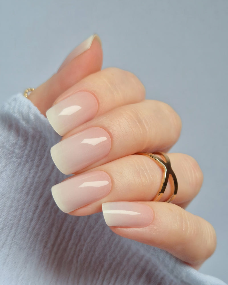 Babyboomer UV-Nagelfolie mit zartem Ombré-Finish in Rosa-Weiß auf Hand vor hellem Hintergrund