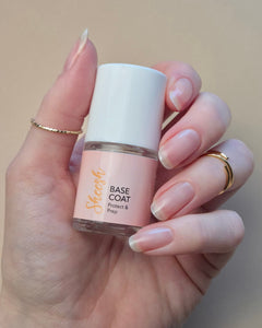 SHEESH Nails Base Coat wird mit Pinsel auf einen Fingernagel aufgetragen vor hellem Studiohintergrund