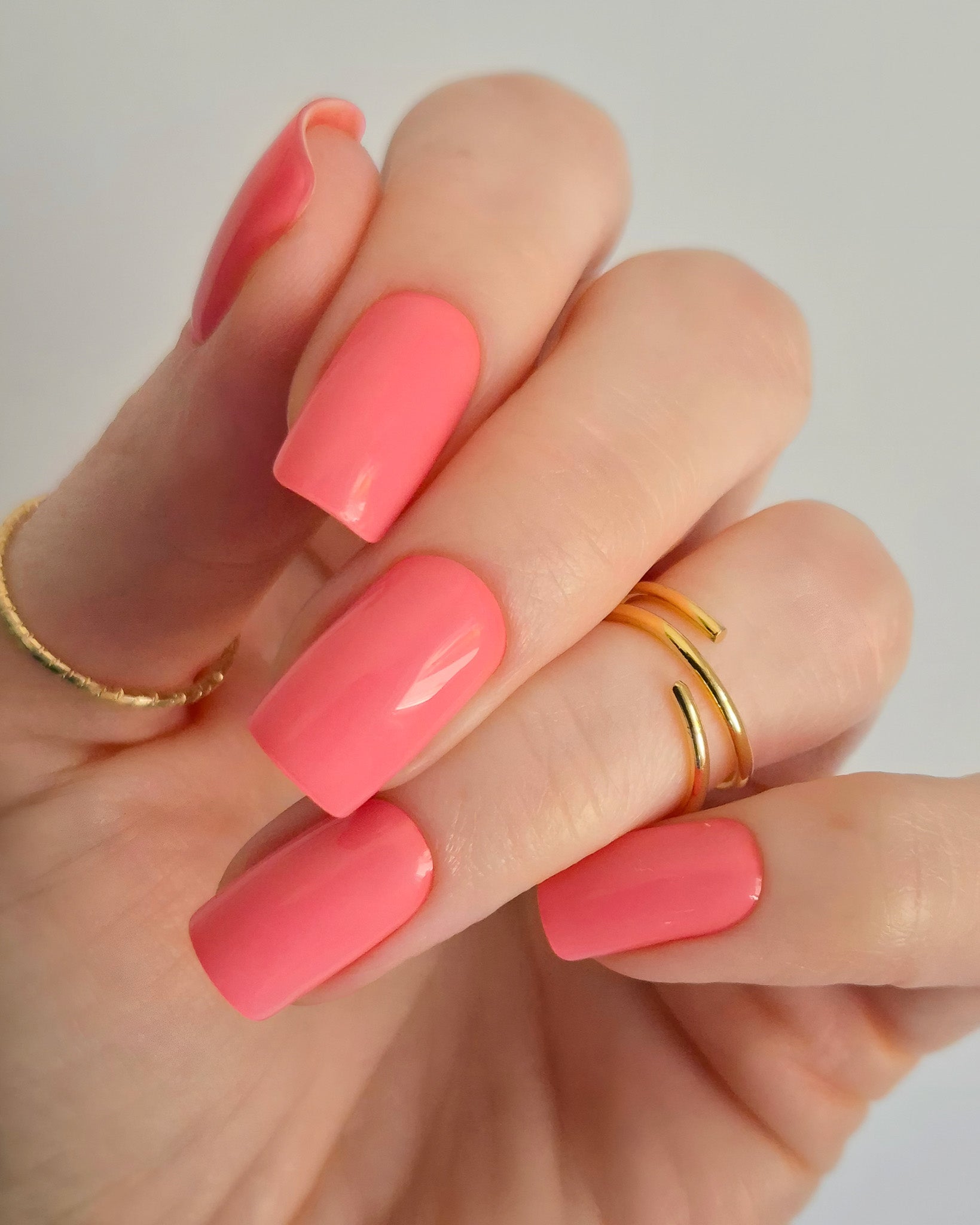 Leuchtend korallrosa UV-Nagelfolien mit glänzendem Finish auf Fingernägeln“