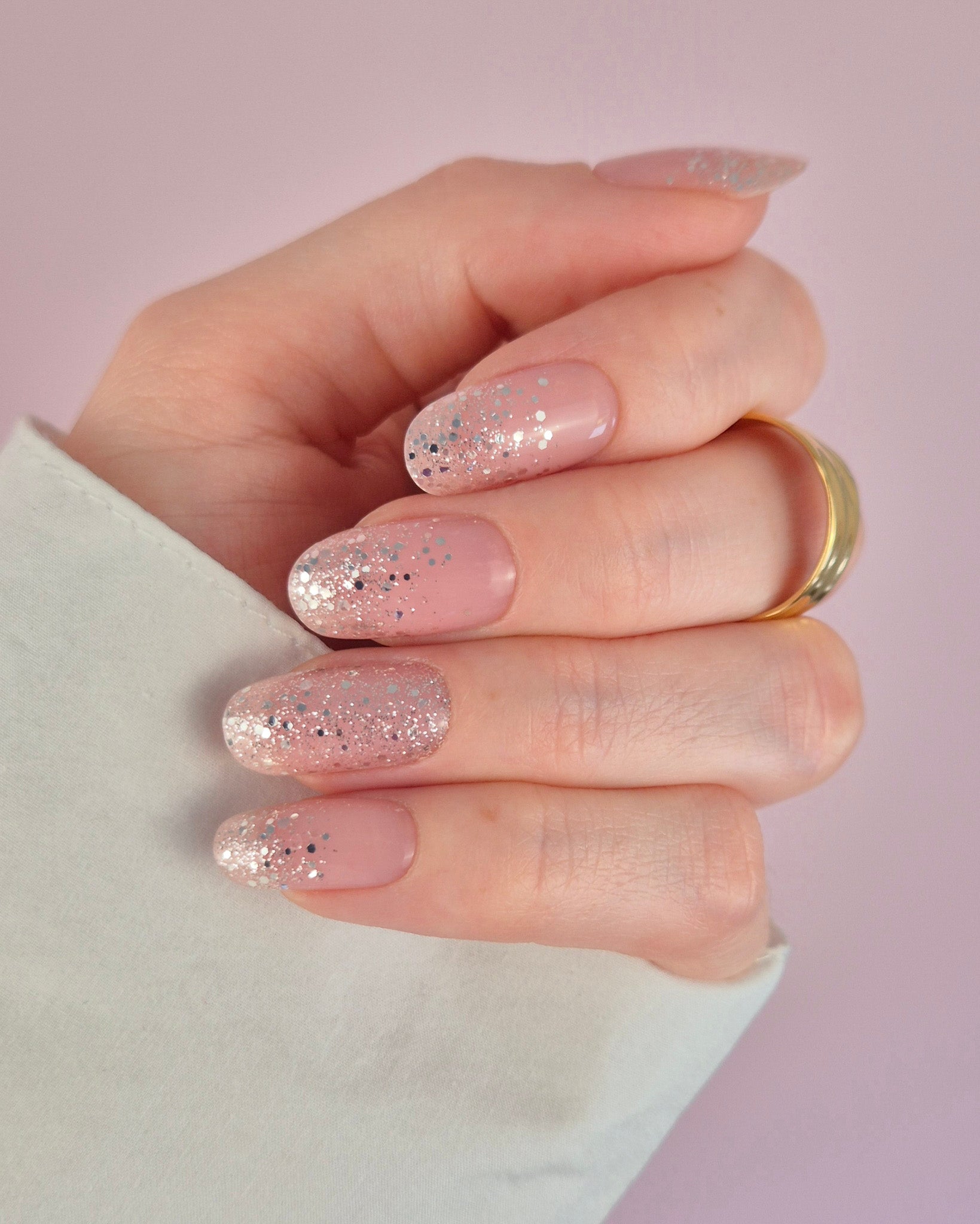 Nahaufnahme einer Hand mit der Sheesh Nails UV-Nagelfolie „Champagne Fizz“. Die Nägel zeigen ein zartes Nude-Rosa, das sanft in funkelnden Silberglitter übergeht. Der Look wirkt edel, festlich und feminin – perfekt für elegante Anlässe, festliche Looks oder einen stilvollen Alltagsglanz.