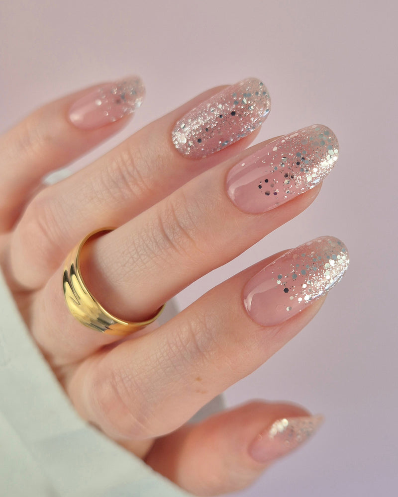 Nahaufnahme einer Hand mit der Sheesh Nails UV-Nagelfolie „Champagne Fizz“. Die Nägel zeigen ein zartes Nude-Rosa, das sanft in funkelnden Silberglitter übergeht. Der Look wirkt edel, festlich und feminin – perfekt für elegante Anlässe, festliche Looks oder einen stilvollen Alltagsglanz.