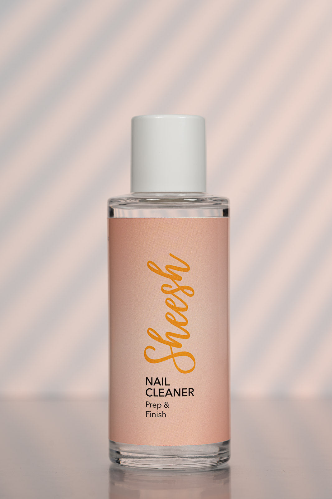 Sheesh Nails Nail Cleaner „Prep & Finish“ – klarer Nagelreiniger in transparenter 100-ml-Flasche mit weißem Deckel, Produktfoto auf roséfarbenem Hintergrund