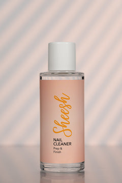Sheesh Nails Nail Cleaner „Prep & Finish“ – klarer Nagelreiniger in transparenter 100-ml-Flasche mit weißem Deckel, Produktfoto auf roséfarbenem Hintergrund