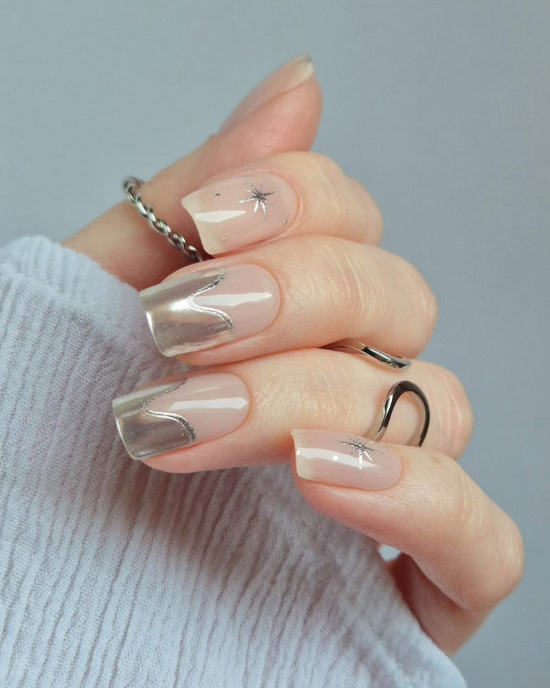 Sheesh Nails – Cosmic Crush – elegante Nagelfolien in transparentem Nude mit silbernem Glitzer und funkelnden Sternmotiven, stilvolles Design für moderne, glamouröse Maniküren. Perfekte Passform und glänzendes Finish für festliche Looks.