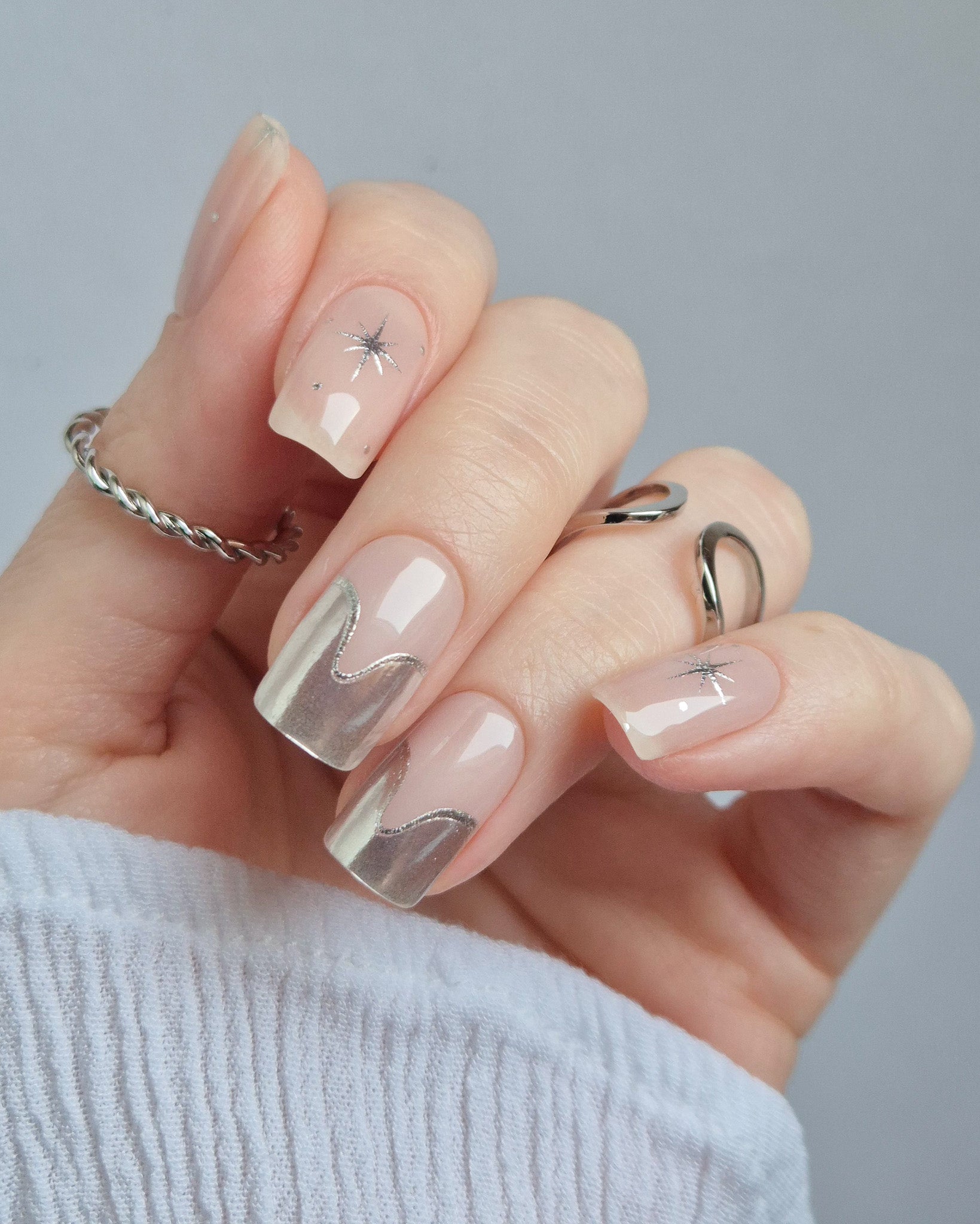 Sheesh Nails – Cosmic Crush – elegante Nagelfolien in transparentem Nude mit silbernem Glitzer und funkelnden Sternmotiven, stilvolles Design für moderne, glamouröse Maniküren. Perfekte Passform und glänzendes Finish für festliche Looks.