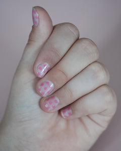 Kinderhand mit rosa Sheesh Nails Kinderfolie „Love“. Die Nagelfolien zeigen kleine, pinke Herzmotive auf transparentem Untergrund und verleihen einen verspielten, liebevollen Look – perfekt für Kinder, die zarte Farben und kreative, herzliche Designs lieben.