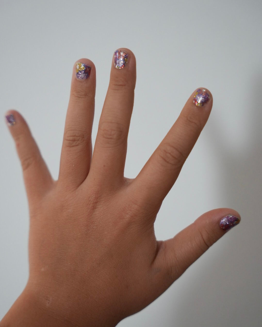 Kinderhand mit rosa Sheesh Nails Kinderfolie „Love“. Die Nagelfolien zeigen kleine, pinke Herzmotive auf transparentem Untergrund und verleihen einen verspielten, liebevollen Look – perfekt für Kinder, die zarte Farben und kreative, herzliche Designs lieben.