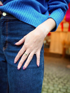 Sheesh Nails Press-on Nails in zartem Rosa-Lila-Ton mit dezentem Glanz und floralem Design. Stilvolle, wiederverwendbare künstliche Fingernägel für einen modernen Alltagslook. Hand mit femininer Maniküre, kombiniert mit Jeans und blauem Pullover – elegantes, trendbewusstes Styling für jeden Anlass.