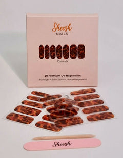 Produktaufnahme der Sheesh Nails UV-Nagelfolie „Catwalk“. Die Folien zeigen ein ausdrucksstarkes Leopardenmuster in warmen Brauntönen mit glänzendem Finish. Das Design wirkt glamourös, trendbewusst und gleichzeitig elegant – ideal für auffällige Maniküren im Animal-Print-Look. Verpackung und Zubehör unterstreichen den hochwertigen, modischen Stil der Marke.