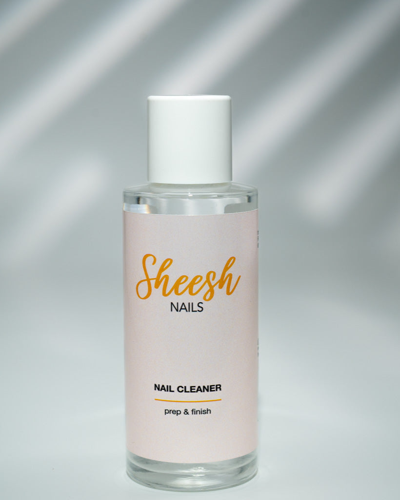 Produktfoto des Sheesh Nails Nail Cleaner. Die elegante Glasflasche mit weißem Deckel und zartrosa Etikett zeigt das Logo „Sheesh Nails“ und die Aufschrift „prep & finish“. Ideal zur Vorbereitung und Reinigung der Nägel vor dem Auftragen von Nagelfolien – sorgt für langanhaltenden Glanz und perfekte Haftung.