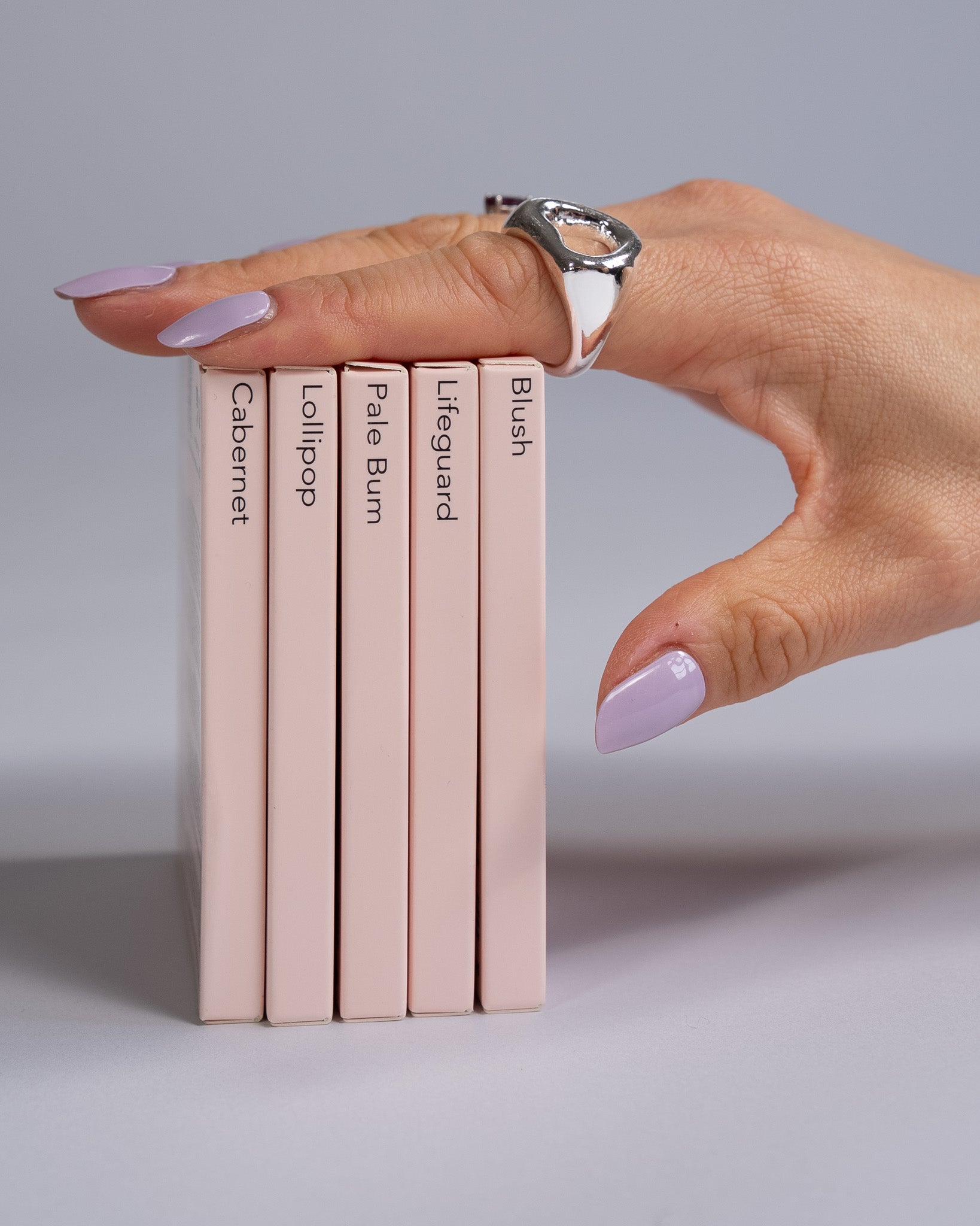 Sheesh UV-Nagelfolien 5er Set – Hand hält fünf verschiedene Sheesh Nagelfolien-Verpackungen in Salonqualität für individuelle Maniküre.