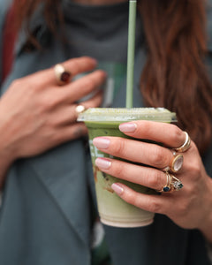Frau hält einen grünen Smoothie und trägt die Sheesh Nails UV-Nagelfolie „Little Secret“. Der sanfte Roséton mit funkelndem Silberglitter verleiht den Nägeln einen eleganten, femininen Look – stilvoll kombiniert mit Goldschmuck für einen modernen Alltagsmoment.