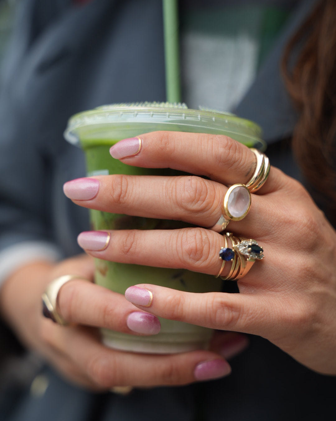 Frau hält einen grünen Smoothie und trägt die Sheesh Nails UV-Nagelfolie „Little Secret“. Der sanfte Roséton mit funkelndem Silberglitter verleiht den Nägeln einen eleganten, femininen Look – stilvoll kombiniert mit Goldschmuck für einen modernen Alltagsmoment.