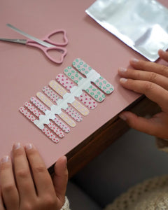 Kinderhände legen bunte Sheesh Nails Kinderfolien „Love“ auf einen rosa Untergrund. Die verspielten Nagelfolien in sanften Rosa-, Grün- und Beigetönen mit Herzmotiven stehen für kreative, liebevoll gestaltete Maniküren – ideal für kleine Nailart-Fans und als kindgerechtes, farbenfrohes Accessoire.