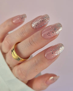 Nahaufnahme einer Hand mit der Sheesh Nails UV-Nagelfolie „Champagne Fizz“. Die Nägel zeigen ein zartes Nude-Rosa, das sanft in funkelnden Silberglitter übergeht. Der Look wirkt edel, festlich und feminin – perfekt für elegante Anlässe, festliche Looks oder einen stilvollen Alltagsglanz.