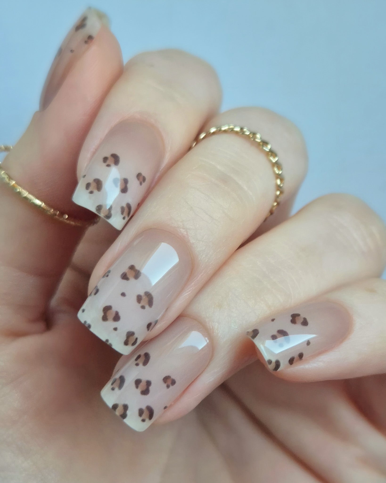 Hand trägt die Sheesh Nails UV-Nagelfolie Half Life. Die Folien zeigen ein transparentes Design mit feinem Leopardenmuster in Braun- und Beigetönen auf zartem Nude-Hintergrund. Der Look wirkt elegant, modern und leicht verspielt – perfekt für trendige Animal-Print-Maniküren mit stilvollem Finish.