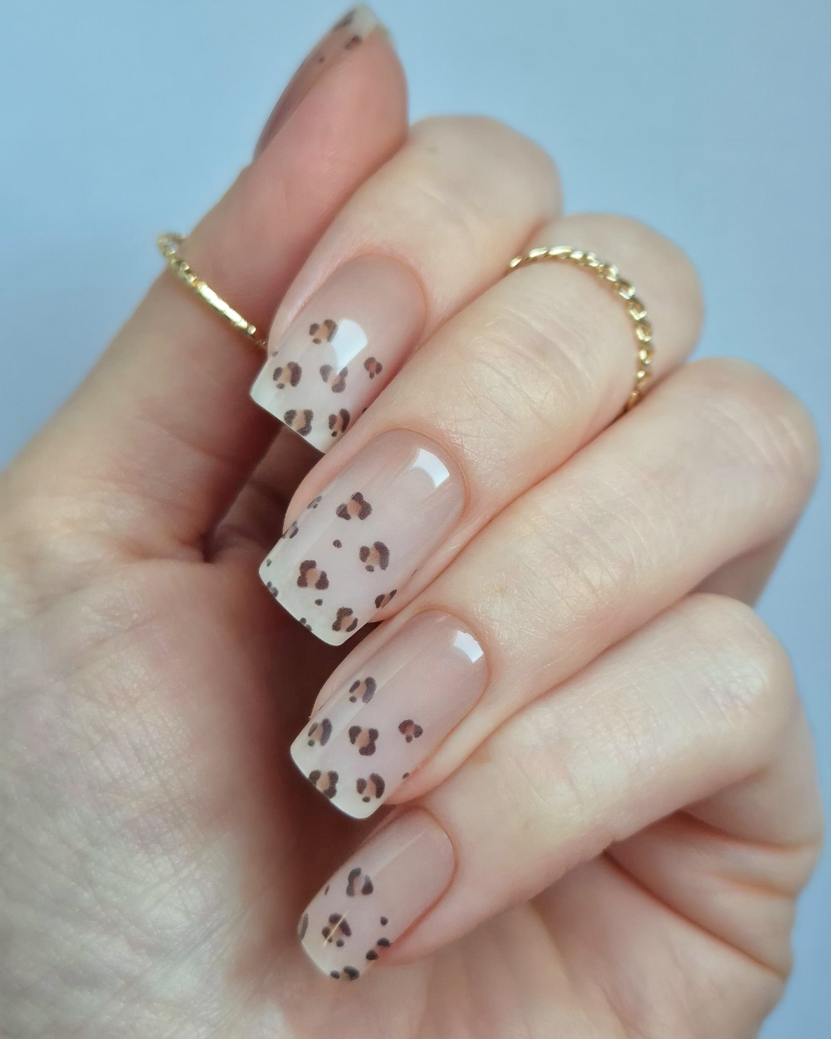 Hand trägt die Sheesh Nails UV-Nagelfolie Half Life. Die Folien zeigen ein transparentes Design mit feinem Leopardenmuster in Braun- und Beigetönen auf zartem Nude-Hintergrund. Der Look wirkt elegant, modern und leicht verspielt – perfekt für trendige Animal-Print-Maniküren mit stilvollem Finish.