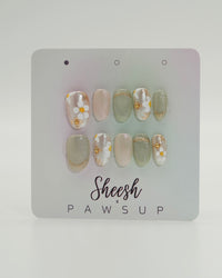 Sheesh Nails x PawsUp Press-on Nails in Grün, Nude und Weiß mit goldenen Details und floralen Mustern. Hochwertige, wiederverwendbare künstliche Fingernägel im eleganten Frühlingsdesign mit Glitzer und Blüten. Edles Press-on-Set für gepflegte Hände – stilvolles Nageldesign mit natürlichem Glamour.