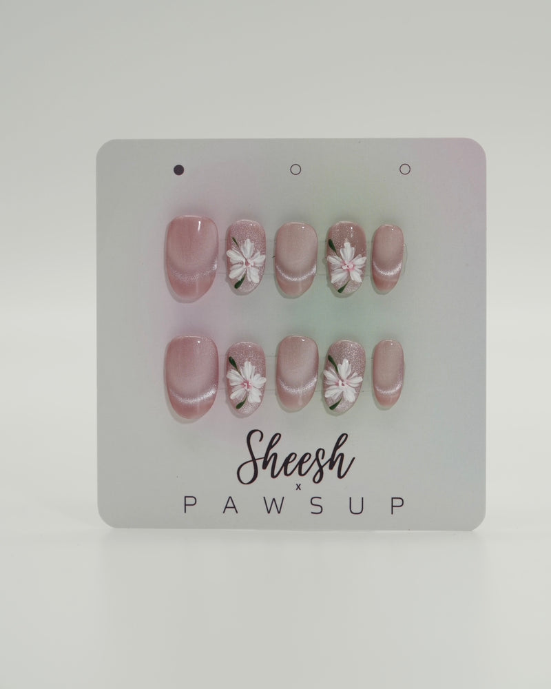 Sheesh Nails x PawsUp Press-on Nails in Rosé mit weißen Blüten und feinem Glitzerverlauf. Hochwertige, wiederverwendbare künstliche Fingernägel im zarten, femininen Design. Handgefertigtes Press-on-Set für elegante Maniküre mit floralen Details – perfekte Kombination aus Natürlichkeit und Glamour.