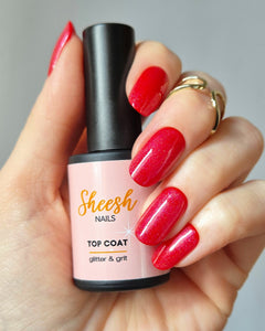 Hand mit glänzend roten Nägeln trägt die Sheesh Nails UV-Nagelfolie „Lifeguard“, veredelt mit dem Topcoat „Glitter & Grit“. Die Kombination sorgt für intensiven Farbglanz und funkelnden Schimmer – ein auffälliger, eleganter Look für gepflegte Nägel und besondere Anlässe.