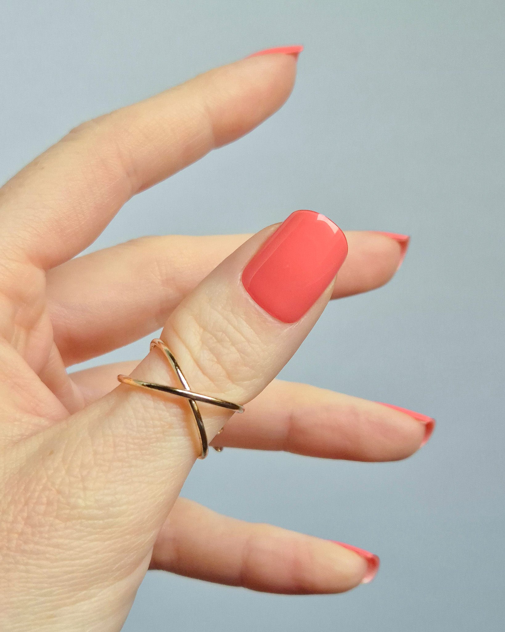 UV Nagelfolien in leuchtendem Korallrot – SHEESH Nails „Lobster Roll“. Hand hält glänzende korallrote Gel-Nagelfolien auf transparenter Trägerfolie. Intensive Sommerfarbe, vegan, selbstklebend und lang haltbar für perfekte Maniküre zuhause.