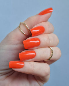 Leuchtend orange-rote UV-Nagelfolien mit glänzendem Finish auf Fingernägeln
