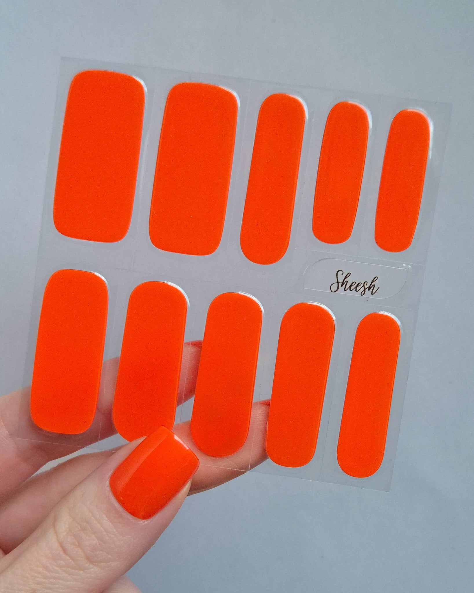 Leuchtend orange-rote UV-Nagelfolien mit glänzendem Finish auf Fingernägeln