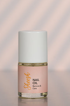 Sheesh Nails Nail Oil „Remove & Care“ – pflegendes Nagelöl in 12-ml-Glasflasche mit weißem Deckel, Produktfoto auf roséfarbenem Hintergrund