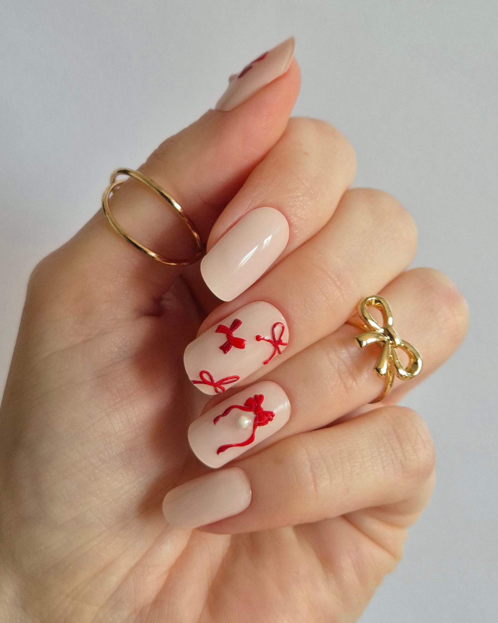 Sheesh Nails Nageldesign mit UV-Nagelfolien – festliches Motiv mit roten Schleifen auf zarten Nägeln, perfekte Maniküre mit Sheesh UV-Folien.