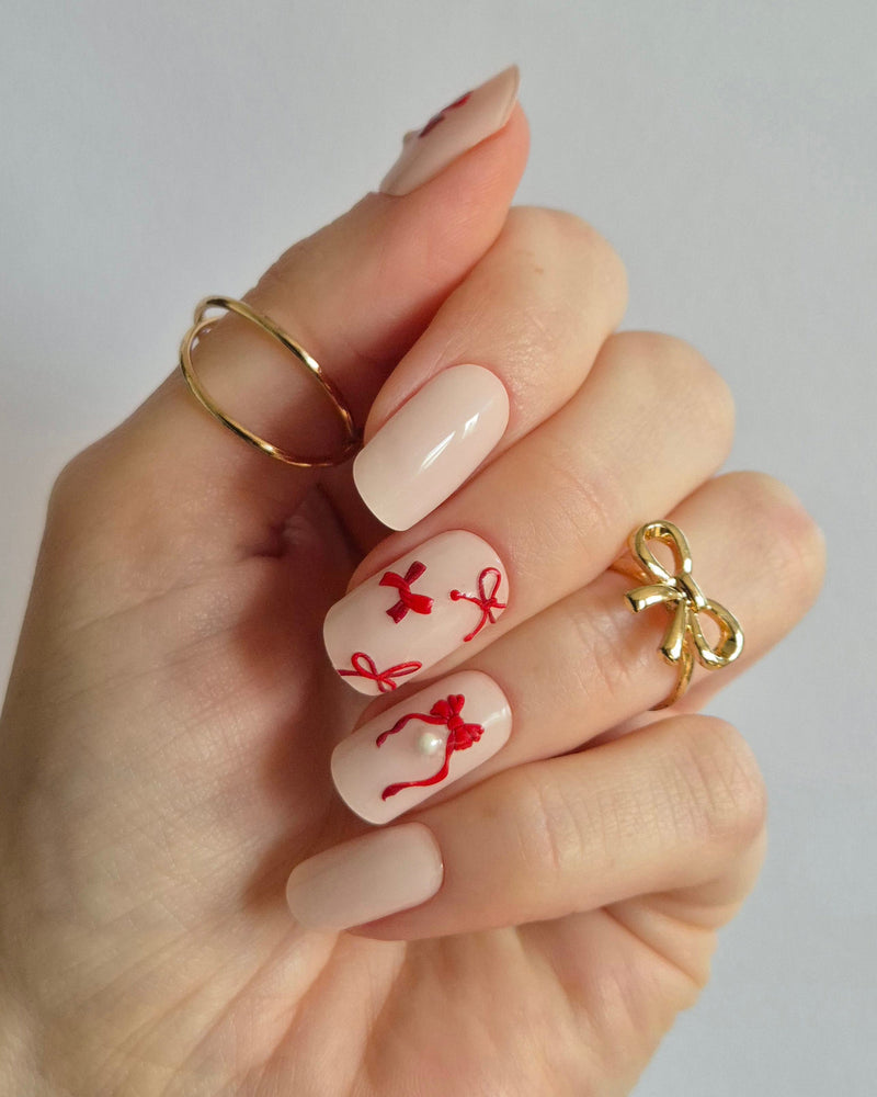 Sheesh Nails Nageldesign mit UV-Nagelfolien – festliches Motiv mit roten Schleifen auf zarten Nägeln, perfekte Maniküre mit Sheesh UV-Folien.