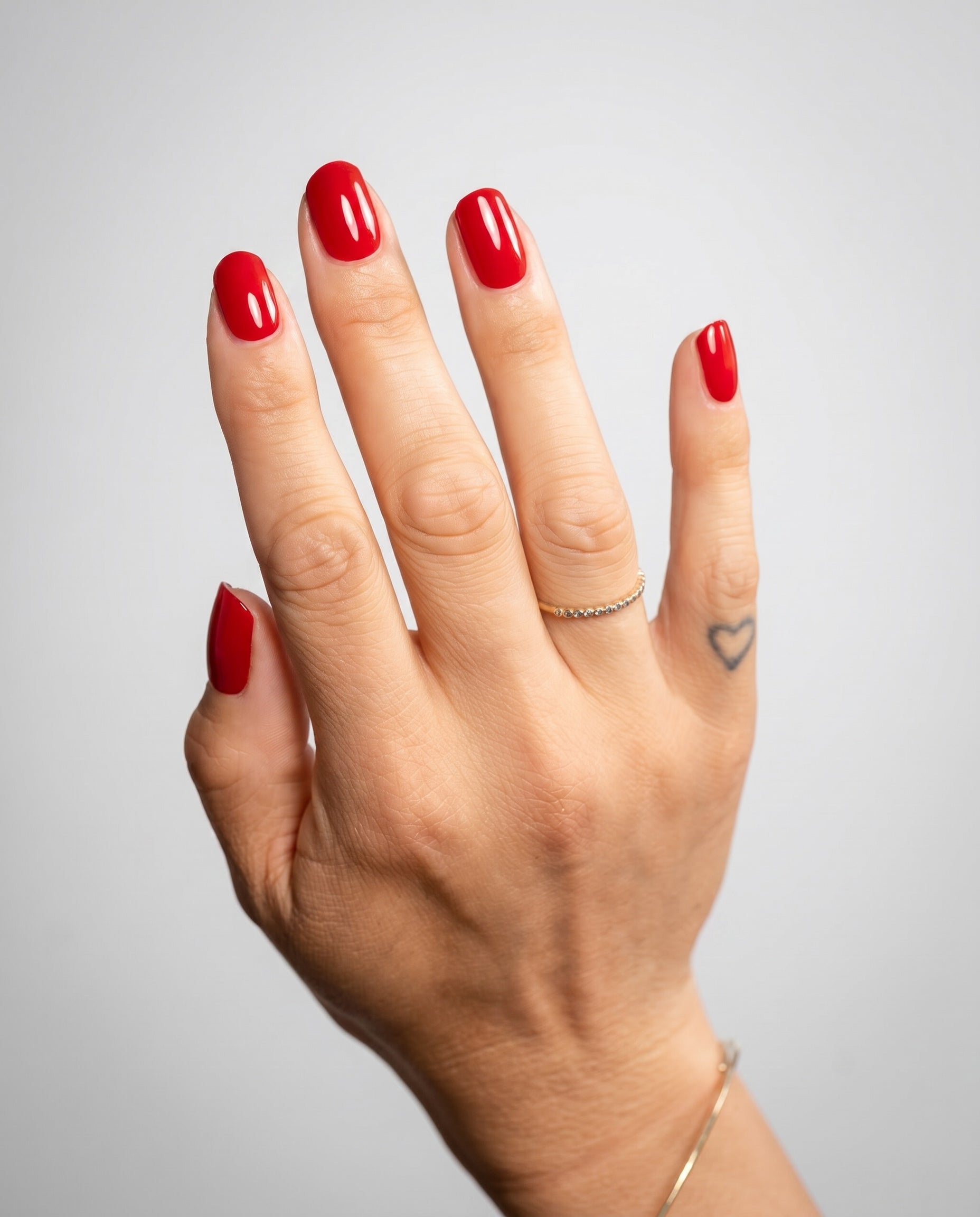 Nahaufnahme einer Hand mit glänzender Red Nude Maniküre 