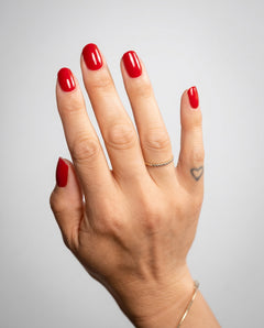 Nahaufnahme einer Hand mit glänzender Red Nude Maniküre 
