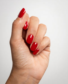 Nahaufnahme einer Hand mit glänzender Red Nude Maniküre 