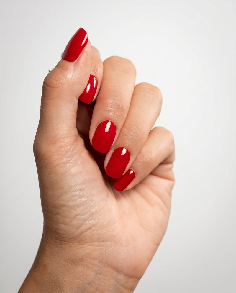 Nahaufnahme einer Hand mit glänzender Red Nude Maniküre 