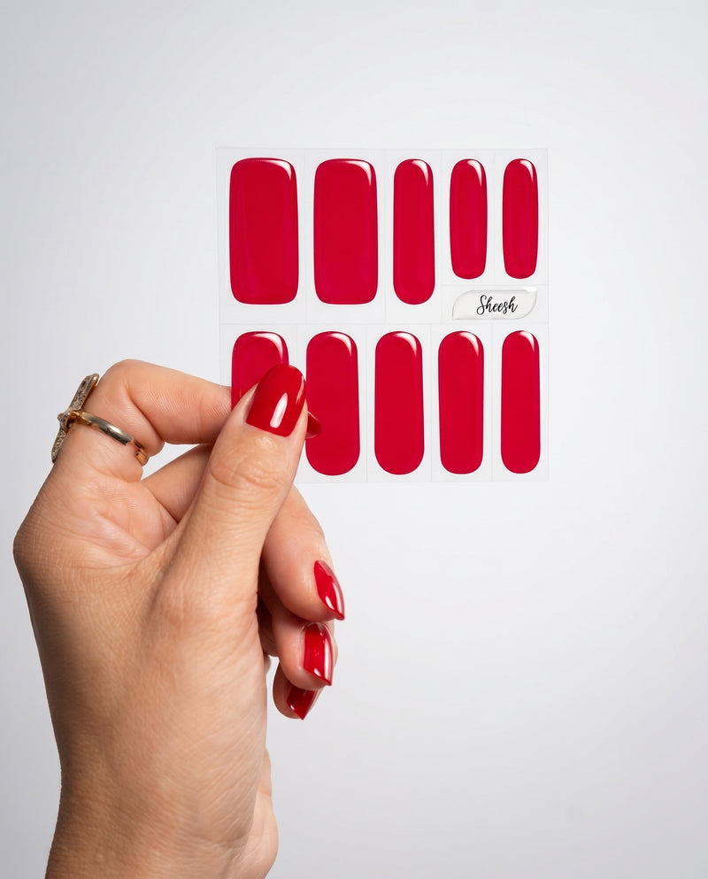 Hand mit glänzenden roten UV-Nagelfolien in der Farbe Red Nude von SHEESH Nails