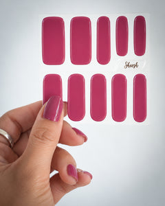 Sunset Pink UV-Nagelfolien von SHEESH Nails auf einem transparenten Folienbogen, gehalten von einer Hand mit passender Maniküre.

