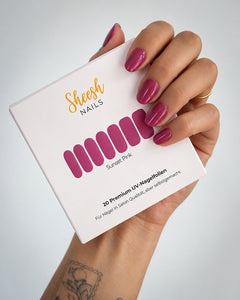 Hand mit glänzenden Nägeln in Beerenpink hält die Sunset Pink Verpackung von SHEESH Nails mit 20 UV-Nagelfolien.
