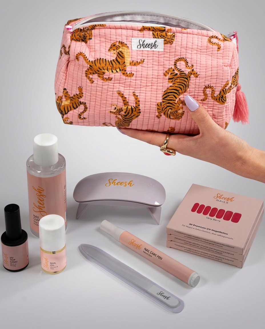 Sheesh Nails Starterset mit rosa Kosmetiktasche mit Tigerprint, UV-Lampe, UV Top Coat, Nail Oil, Nail Care Pen, Glasfeile, Nail Cleaner und drei Packungen UV-Nagelfolien auf weißem Hintergrund
