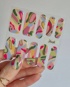 SHEESH Nagelfolie Arty, entworfen in Kooperation mit der abstrakten Künstlerin Robyn Cher Klittich. Die Nägel zeigen ein farbenfrohes, künstlerisches Design in Rosa-, Gelb-, Grün- und Blautönen. Inspiriert von moderner Malerei vereint Arty Farbe, Emotion und Kreativität – eine Limited Edition für alle, die Nail Art lieben.