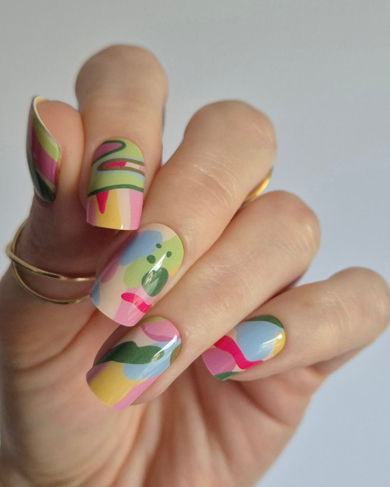 SHEESH Nagelfolie Arty, entworfen in Kooperation mit der abstrakten Künstlerin Robyn Cher Klittich. Die Nägel zeigen ein farbenfrohes, künstlerisches Design in Rosa-, Gelb-, Grün- und Blautönen. Inspiriert von moderner Malerei vereint Arty Farbe, Emotion und Kreativität – eine Limited Edition für alle, die Nail Art lieben.