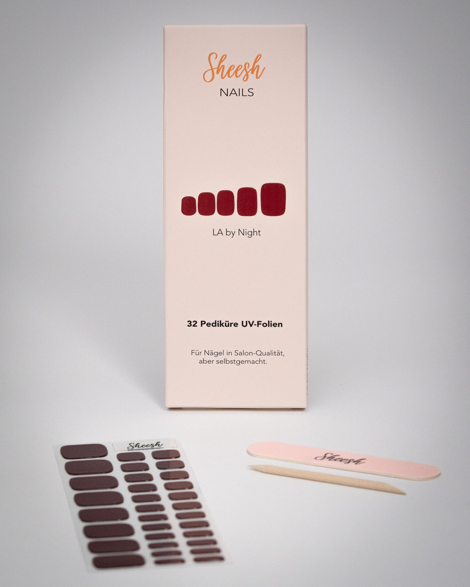 Sheesh Nails Pediküre UV-Folien „LA by Night“ in elegantem Dunkelrot. Verpackung mit 32 UV-Folien, Nagelfeile und Holzstäbchen auf weißem Hintergrund. Für eine langanhaltende Pediküre in Salon-Qualität – einfach mit UV-Licht 